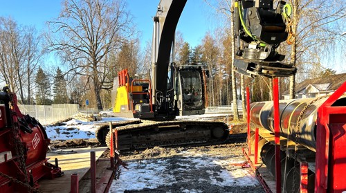 Grävmaskin som laddar med rör